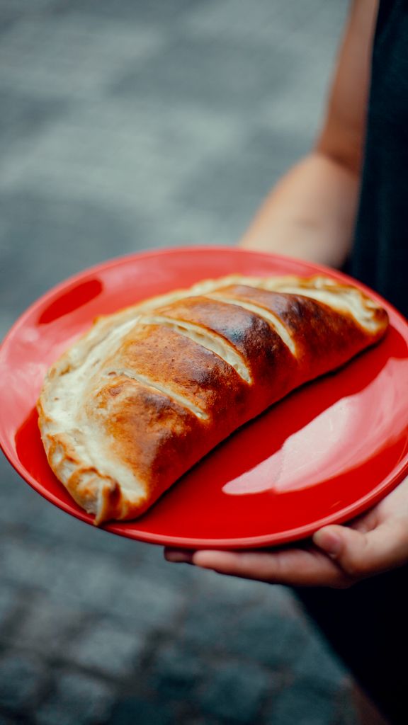A close-up of a calzone served on a red plate, perfect for food photography.
